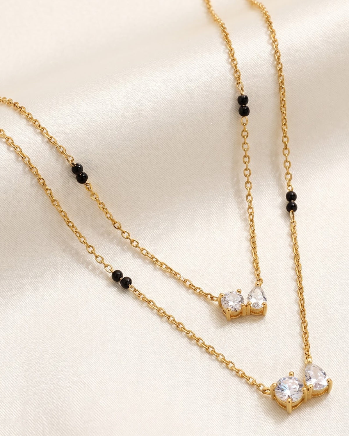 Solvyn Stone Duo Mangalsutra — gold-tone double chain mangalsutra with black beads and CZ stone duo, laid flat