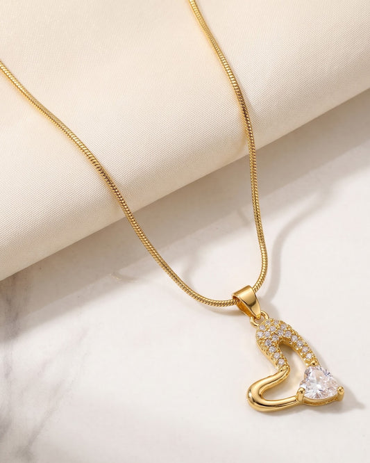 Solreen Halo Heart Pendant Necklace — gold-tone asymmetric heart pendant with pavé CZ halo and CZ solitaire, laid flat