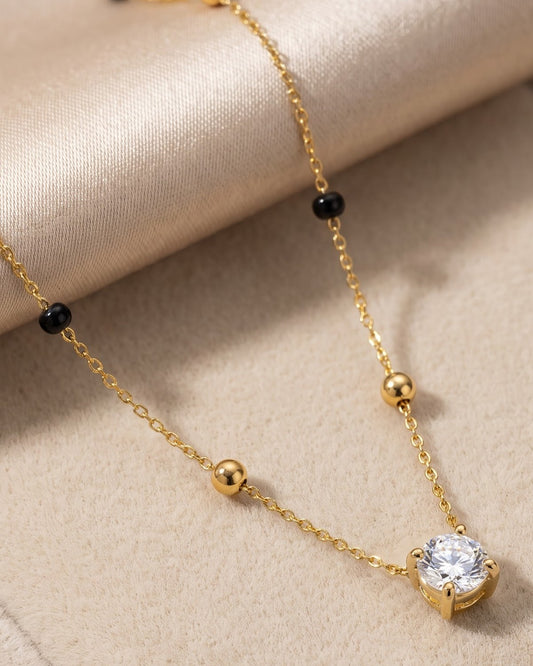 Solyma Round Solitaire Mangalsutra — a round-cut cubic zirconia solitaire on gold-tone chain with black beads, hero shot, laid flat