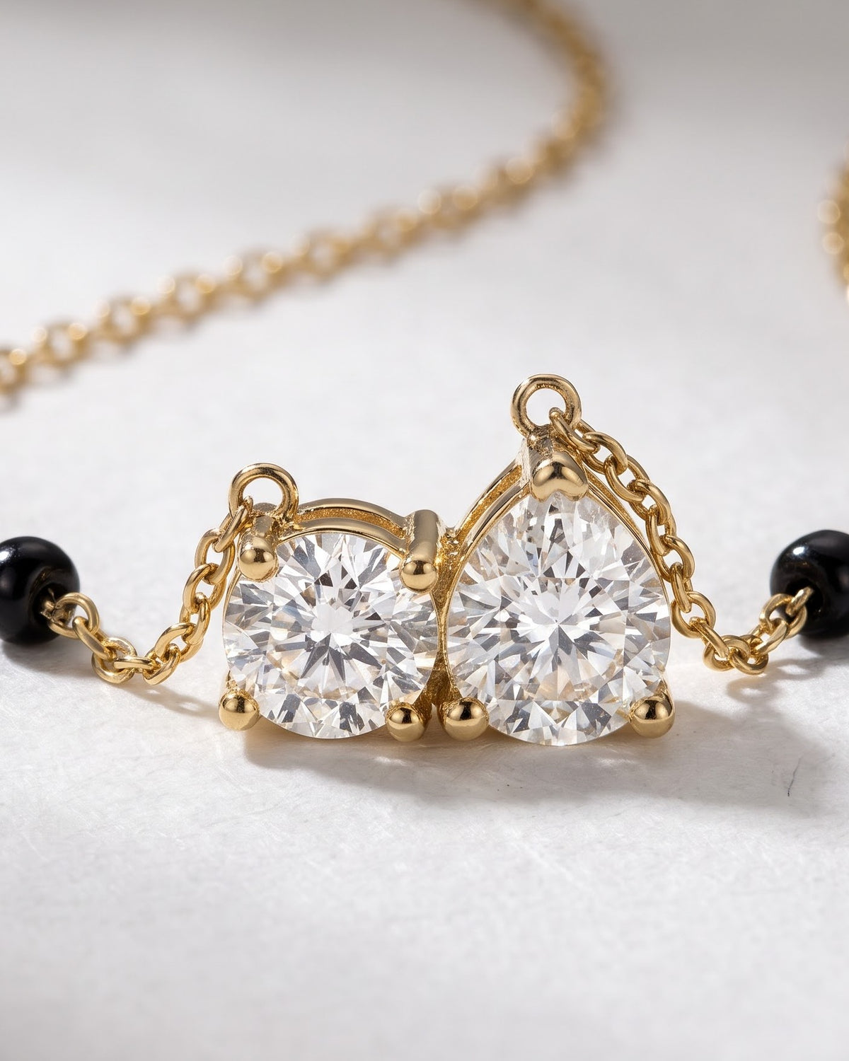 Cinematic close-up of the Solveya Drop Duo Mangalsutra chain and a pear-cut and round-cut cubic zirconia duo