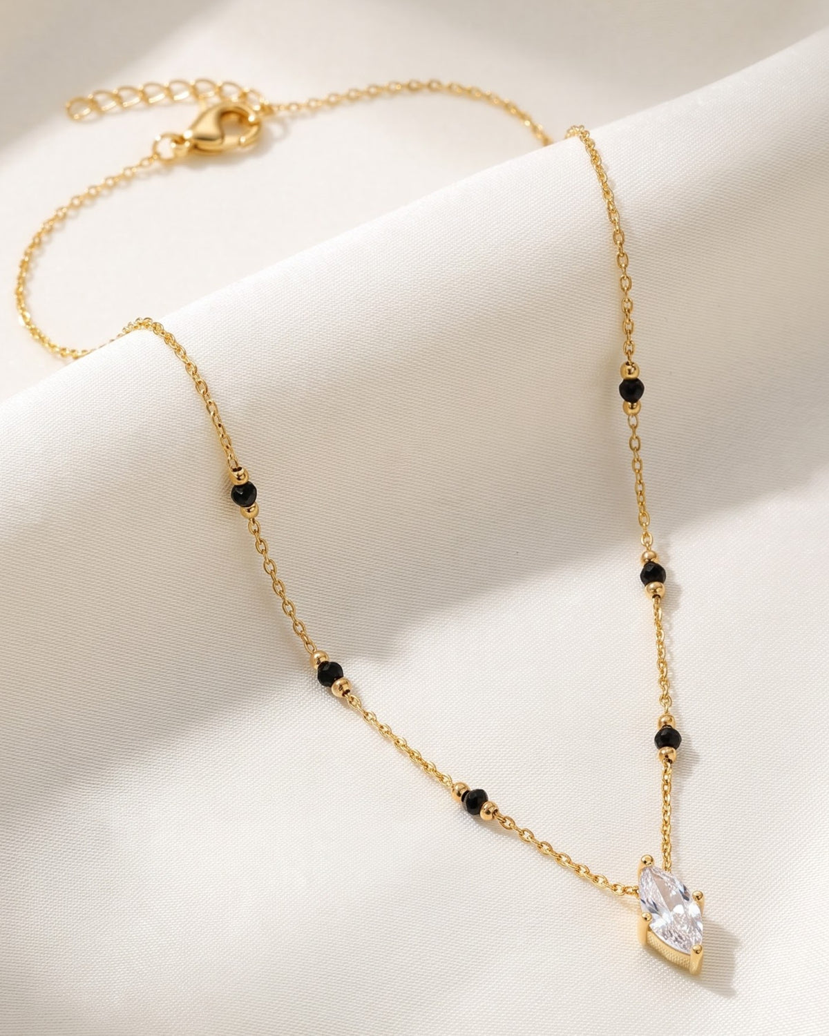 Solvena Marquise Solitaire Mangalsutra — a marquise-cut cubic zirconia solitaire on gold-tone chain with black beads, hero shot, laid flat