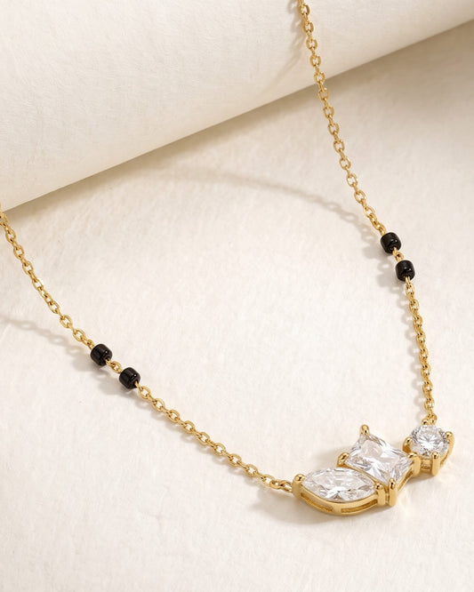 Solyra Stone Trio Mangalsutra — a marquise, princess-cut and round cubic zirconia trio on gold-tone chain with black beads, hero shot, laid flat