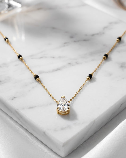 Solveth Drop Solitaire Mangalsutra — a pear-cut cubic zirconia solitaire on gold-tone chain with black beads, hero shot, laid flat